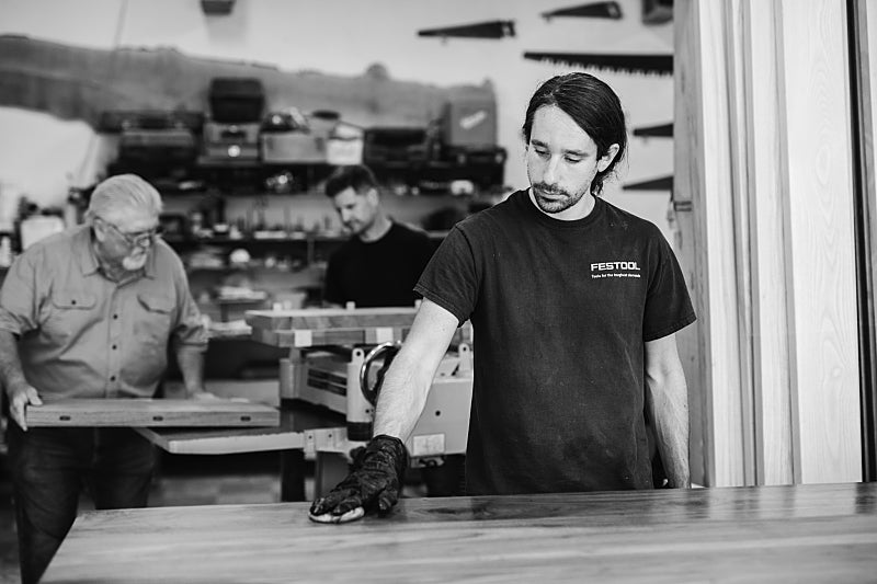 Artisan workshop scene - craftsman hand-finishing contemporary wood furniture in British Columbia studio