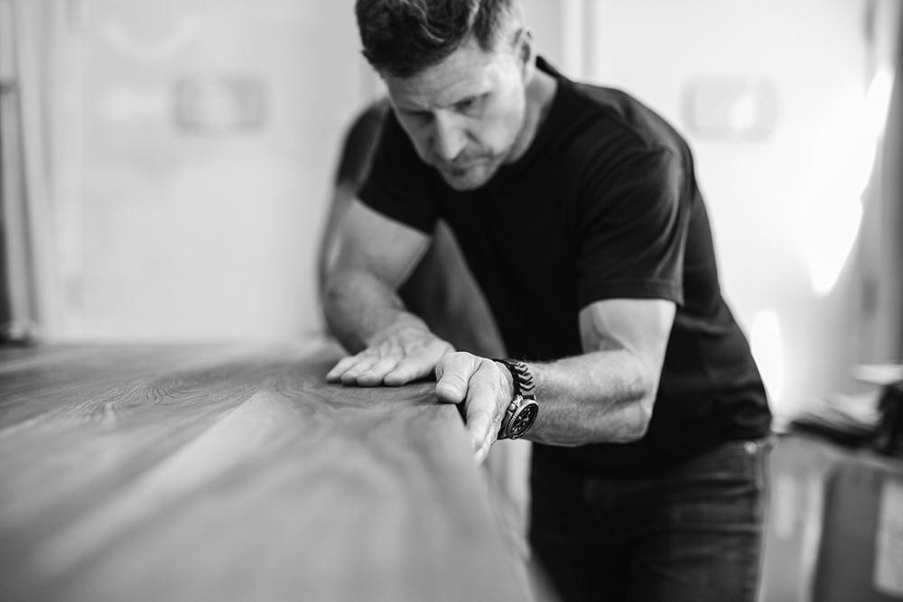 Artisan workshop scene - craftsman hand-finishing contemporary wood furniture in British Columbia studio