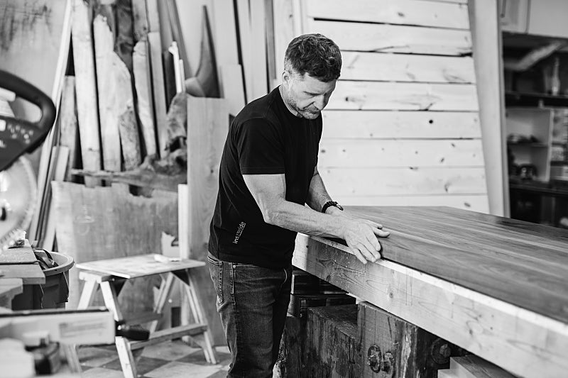Kirk Van Ludwig sanding a solid wood slab by hand in the Victoria BC studio—capturing the analogue craftsmanship and founder-led design ethos of Autonomous Furniture.